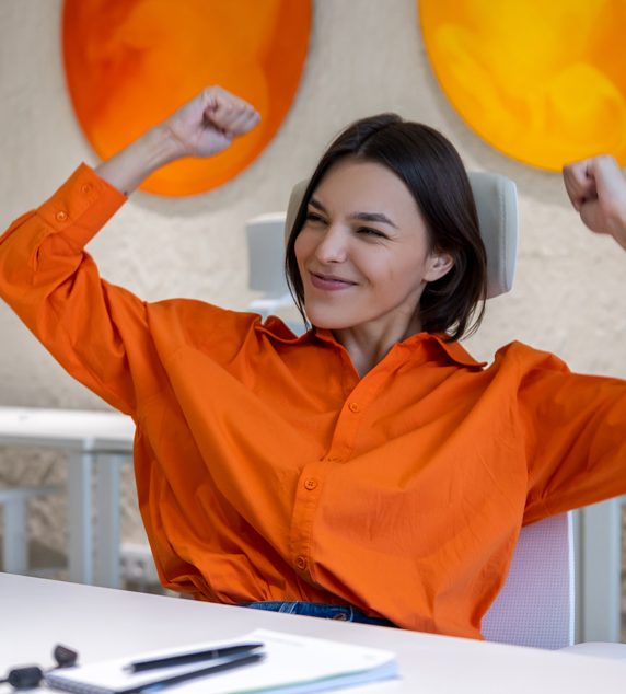 smiling-happy-young-female-office-worker-seated-desk-looking-computer-monitor
